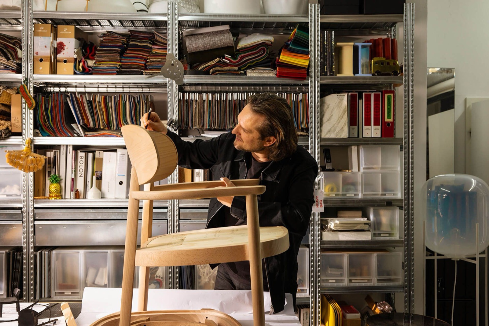 Sebastian Herkner in his studio, at work amid the material and colour samples his projects begin from.