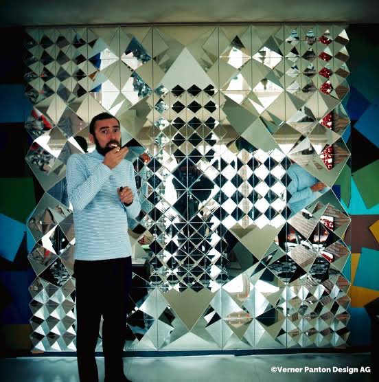 Verner Panton in front of a mirrored diamond-tile wall installation. Photo © Verner Panton Design AG